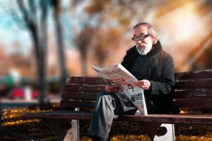 a man sitting on a bench reading a newspaper