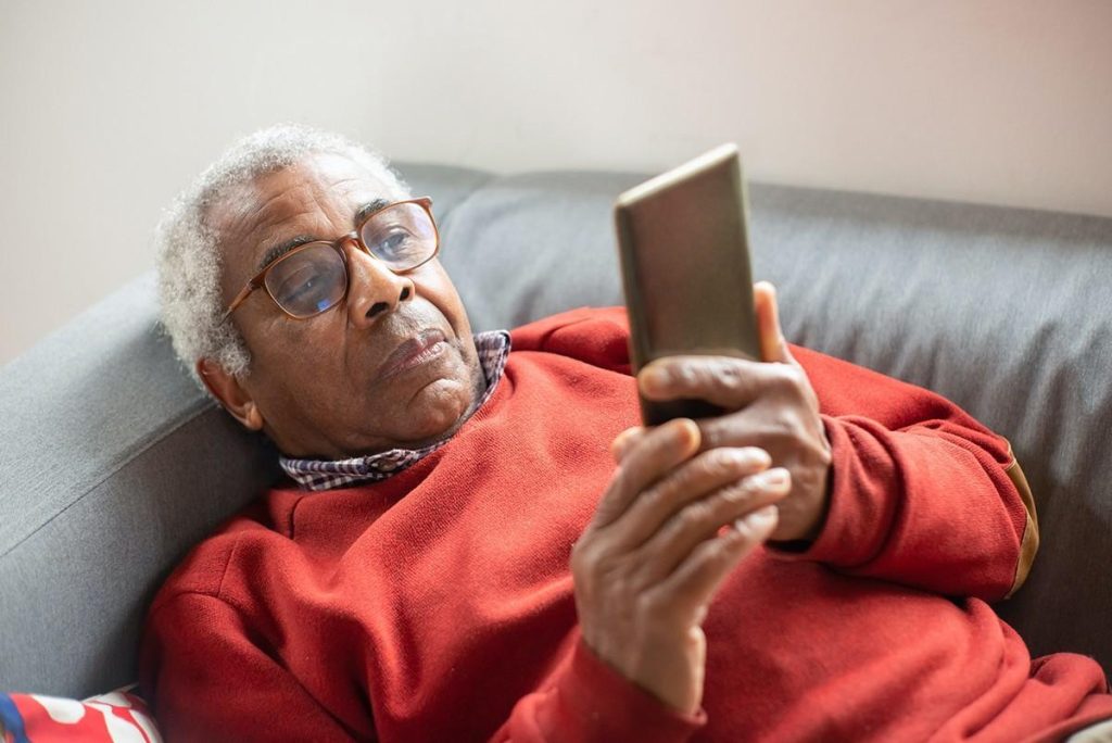 a man lying on a couch looking at a cell phone