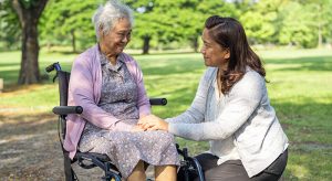 a woman sitting in a wheelchair with a woman in a park