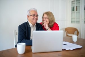 a man and woman sitting at a table looking at a laptop