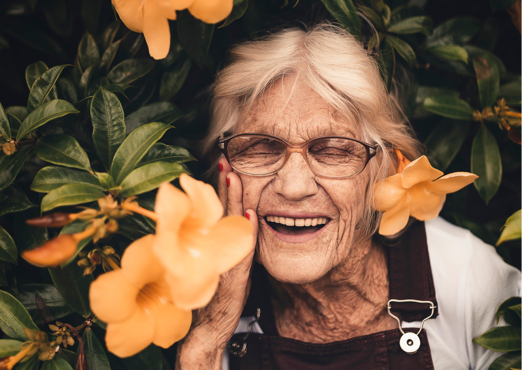 an elderly woman smiling with flowers around her face