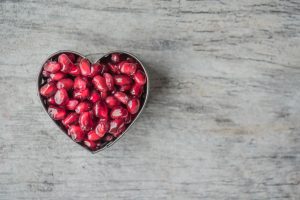 a heart shaped bowl filled with pomegranate seeds