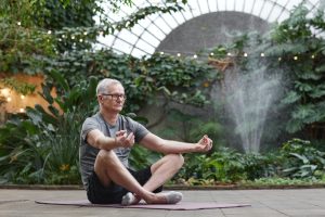 a man sitting on a yoga mat in front of a fountain