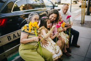 a group of people sitting on a bench holding flowers