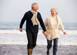 a man and woman holding hands on a beach