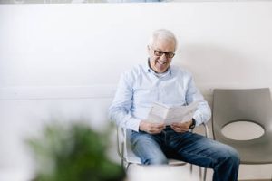 a man sitting in a chair reading a newspaper