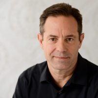 Photo of a Total Life therapist - white man wearing a black collared shirt on a white background.