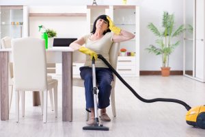 Senior old woman tired after vacuum cleaning house