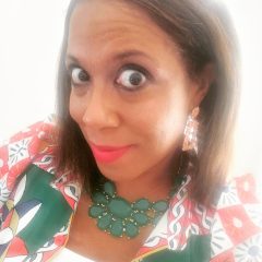 A vibrant therapist from Total Life with straight brown hair, wearing bold earrings, a colorful patterned jacket, a statement green necklace, and a white top, photographed in bright natural light.