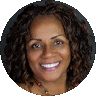 A professional headshot of a smiling woman with curly hair, wearing a colorful necklace, set against a neutral background. She appears confident and approachable, is a therapist at Total Life.