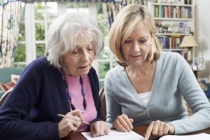 Female Neighbor Helping Senior Woman To Complete Form