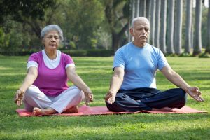 a man and woman sitting on a mat in a park