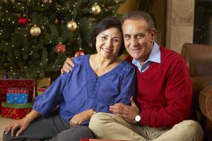 a man and woman sitting together in front of a christmas tree