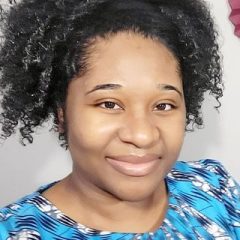 Portrait of a smiling therapist at Total Life with medium skin tone and naturally curly hair, wearing a blue patterned blouse in an indoor setting with a softly blurred background.