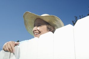 Woman peering over garden fence