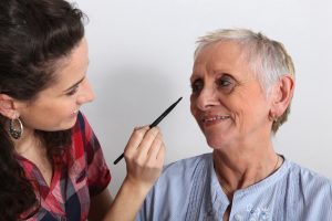 Woman helping to apply make-up